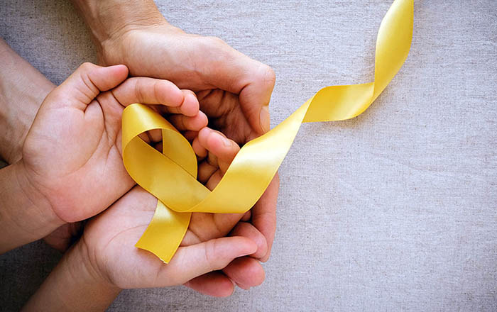 adult and child hands holding yellow gold ribbon, Sarcoma Awaren